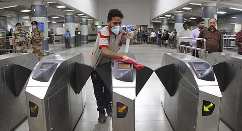 A cleaning staff disinfects the entry gates at the Rajiv Chowk Metro station in Delhi. (Photo | Anil Shakya, EPS)