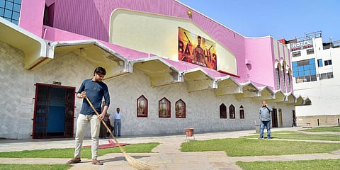A worker sweeps the lawn of a closed cinema hall in view of the novel coronavirus outbreak in Bikaner. (Photo| PTI)