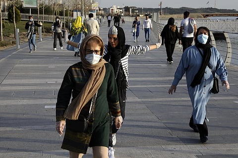 People wearing face masks exercise on the shore of an artificial lake, in Western Tehran, Iran. (Photo | AP)