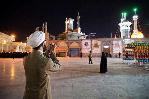 A cleric prays outside the Fatima Masumeh shrine in Iran's holy city of Qom (Photo | AFP)