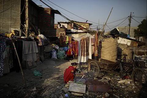 In this Tuesday, March 17, 2020 photo, a woman fills a plastic bottle with pipe water next to a drain filled with plastic and other filth at a slum in New Delhi, India. (Photo | AP)