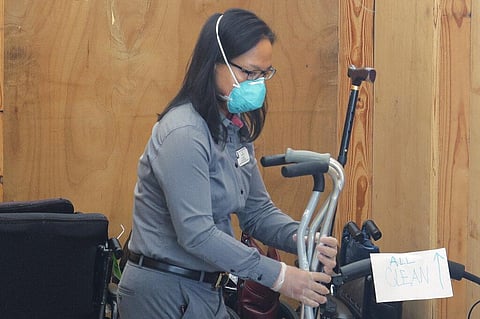 A worker at the Life Care Center in Kirkland, Wash., wears a mask as she sorts canes and other mobility aids that have been cleaned as they are stored in a portable container outside the center in Kirkland, Wash., Tuesday, March 17, 2020, near Seattle. (P