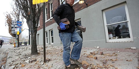 Fred Moesinger, owner of BTG Wine Bar and Caffe Molise in Salt Lake City, picks up bricks among debris that fell from his building after a earthquake hit early on Wednesday. (Photo| AP)