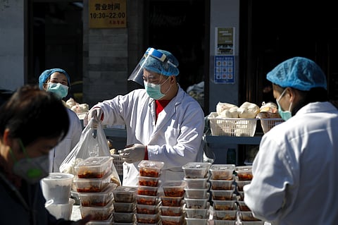 Workers wearing protective face masks pack food orders for customers outside a restaurant only offering take-out business to prevent people gathering following the coronavirus outbreak in Beijing, Sunday, March 1, 2020. (Photo | AP)