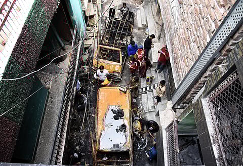 Workers clear burnt vehicles at riot-hit Khajuri Khas in New Delhi. (Photo | Parveen Negi, EPS)