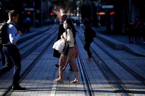 A woman wearing a face mask, amid concerns of the COVID-19 coranavirus, walks on a street in Sydney on March 19, 2020. (Photo | AFP)