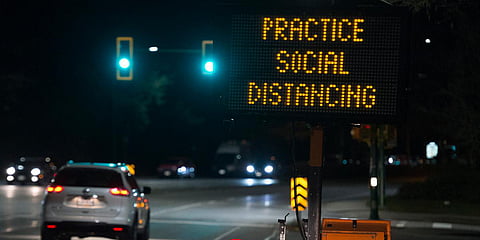 A sign reminding people about 'social distancing' in the midst of the coronavirus outbreak stands next to a roadway in North Vancouver, British Columbia, Canada. (File photo| AP)