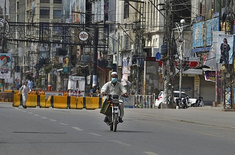 A motorcyclist wears a protective face mask while drives through a market closed due to restrictions put in place over the spread of the coronavirus in Rawalpindi, Pakistan. (Photo | AP)