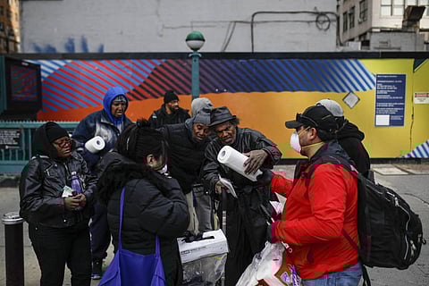 elix Guzman, right, and his wife Virna wear protective gloves and masks due to COVID-19 concerns as they hand out disposable gloves and sanitizing wipes to a group of people who are homeless on 34th Street, Saturday, March 21, 2020, in New York. (PHOTO |