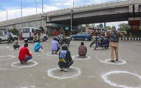 Policemen punish offenders, seated in marked circles to maintain social distancing, who violated the lockdown guidelines by venturing out of their homes unnecessarily during the 21-day complete lockdown to contain the spread of the novel coronavirus, at V