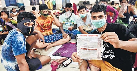 A migrant worker shows his reserved train ticket as he is put up at a community hall in Chinthadripet, following the cancellation of trains. (Photo | P Jawahar/EPS)