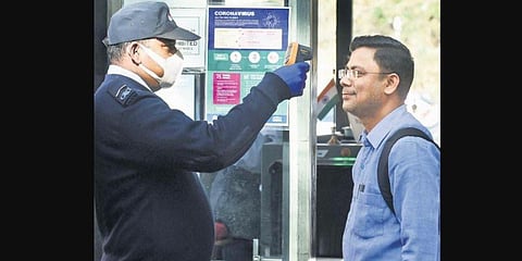 A security guard runs a check on the body temperature of a visitor to an office in New Delhi on Monday. (Photo| Parveen Negi, EPS)