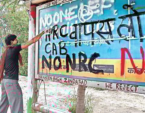 A man clears anti-CAA graffiti painted on a bus stop after the protest site was cleared at Shaheen Bagh in New Delhi.