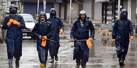 Srinagar Municipal Corporation (SMC) sanitization team walk amid rains during lockdown to contain the spread of coronavirus. (Photo| ANI)