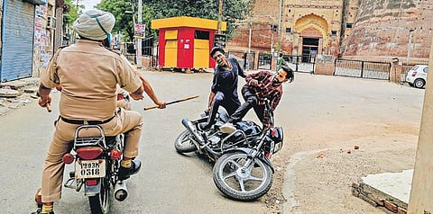 Police personnel charge at a biker for flouting lockdown guidelines, imposed in the wake of coronavirus pandemic, near Razia Sultana Fort in Bathinda, Punjab, on Tuesday | PTI