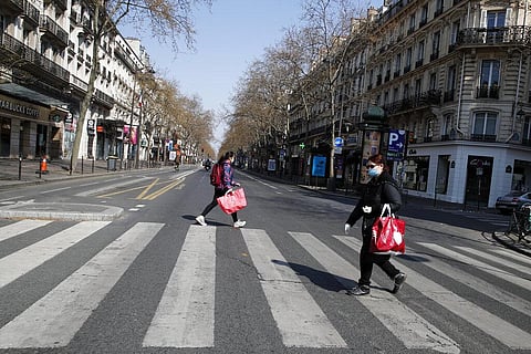 People wearing protective masks cross the deserted Boulevard Sebastopol during the lockdown of coronavirus, in Paris, Friday, March 27, 2020. (Photo | AP)