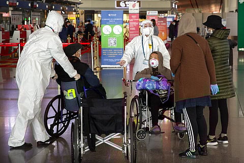 Workers in protective suits prepare to escort travelers in wheelchairs at Beijing Capital International Airport in Beijing, Saturday, March 28, 2020. (Photo | AP)