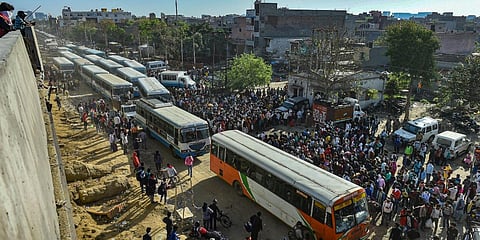 Migrant workers along with their family members wait to board buses to their respective villages, amid a nationwide lockdown in wake of coronavirus pandemic, at Lal Quarter Bus Stand in New Delhi. (Photo| PTI)