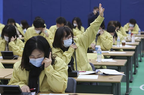 A government official gestures as she and her colleagues make a phone call to the members of Shincheonji Church of Jesus to check if they have symptoms of suspected COBID-19 illness or not, at Goyang City Hall in Goyang, South Korea, Tuesday, March 3, 202