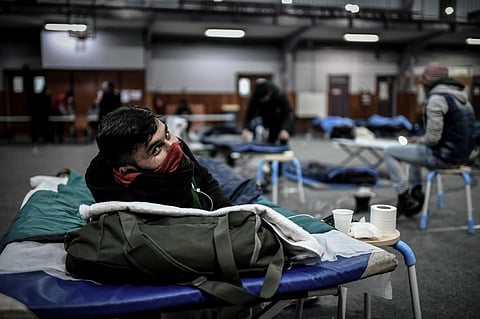 A man, with his face wrapped in scarf, reacts as he rests in bed at the Jean Jaures gymnasium which has been organised to welcome migrants on March 29, 2020 in Paris. (Photo | AFP)