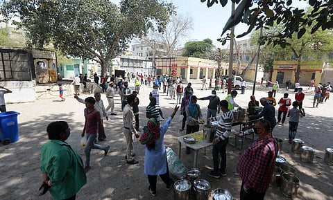 Migrants waiting to get food distributed by SDMC at a school in New Delhi. (Photo | Shekhar Yadav, EPS)