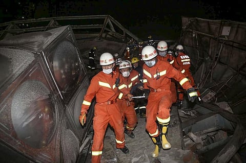 Rescuers carry an injured man (C) out of the rubble of a collapsed hotel in Quanzhou, in China's eastern Fujian province. (Photo | AFP)