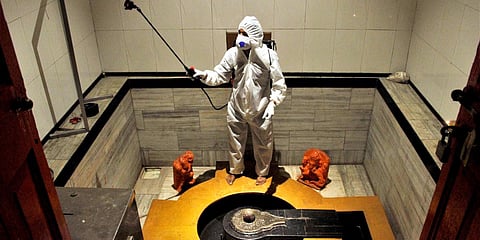 A worker wearing a protective suit disinfects a temple as a preventive measure against the spread of coronavirus disease, in Mumbai. (Photo| ANI)