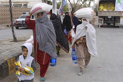 People carry sacks of wheat flour and other food supplies provided by the Saylani Welfare Trust during a lockdown in Quetta, Pakistan, Tuesday, March 31, 2020. (Photo | AP)