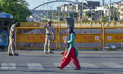 A migrant walks past police barricades placed near Ghazipur during a nationwide lockdown. (Photo | PTI)