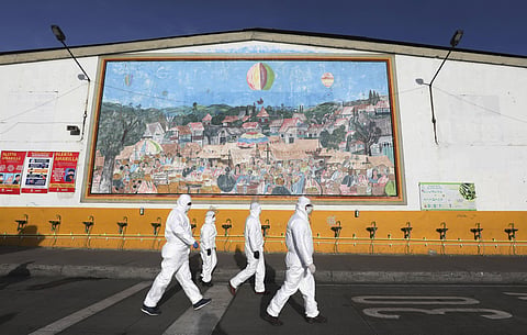 Workers in protective body suits walk past sinks for hand washing at the 'Corabastos,' one of Latin America's largest food distribution centers. (Photo | AP)