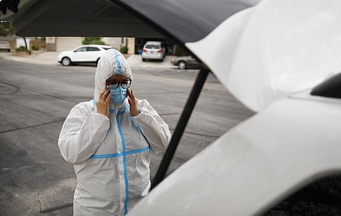 Paramedic Chelsea Monge, of Ready Responders, dons personal protective gear before making a house call for a possible coronavirus patient Friday, April 10, 2020, in Henderson, Nevada. (Photo | AP)