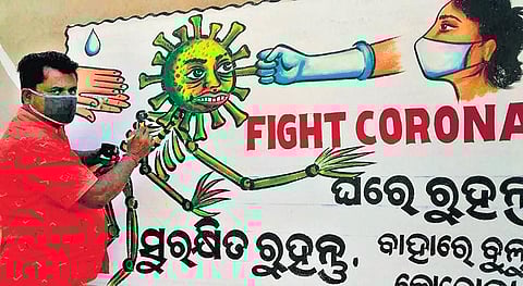 Artist Durga Prasad Mohapatra busy painting a wall in Athagarh | Express