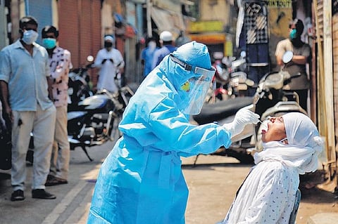 A medic collects swab from the mouth of a woman resident for COVID-19 test in a containment zone at Kurla in Mumbai on Tuesday | PTI