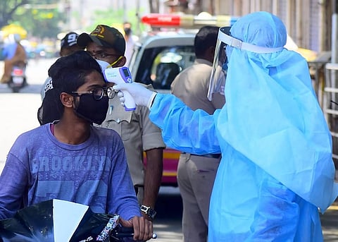 A healthworker checking the temperature of a motorist in Bengaluru. (Photo | Pandarinath B, EPS)