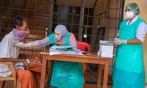 A healthcare worker checking a man for COVID-19 symptoms . (Photo | PTI)