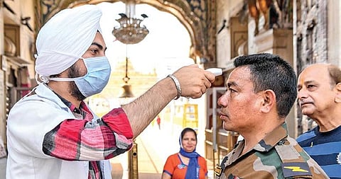A health worker wearing a mask checks the body temperature of a soldier (Photo | AFP)