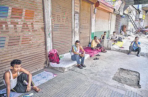 Migrant workers rest outside closed shop during lockdown in Prayagraj. (File Photo)