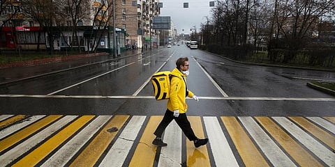 Sergey Nochovnyy wearing a face mask on his way to pick up a food order to deliver. (Photo | AP)