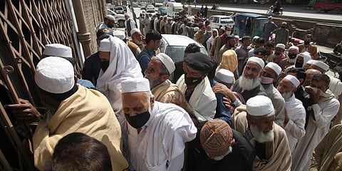 Pakistani government employees crowd together waiting to receive their salaries ignoring social distancing recommendations to help avoid the spread of coronavirus, outside a bank in Peshawar. (Photo| AP)
