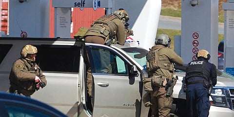 Royal Canadian Mounted Police officers surround a suspect at a gas station in Enfield, Nova Scotia, Sunday. (Photo | AP)