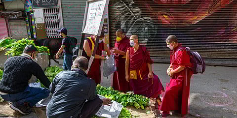 Exile Buddhist nuns and monks wear masks to protect themselves from coronavirus infection as they buy vegetables at a roadside stall in Dharmsala. (Photo | AP)