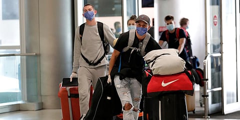 Passengers wearing protective masks and gloves arrive at Miami International Airport for a charter flight on South African Airways (SAA) to Johannesburg. (Photo| AP)