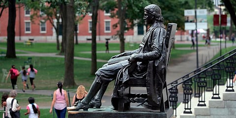 Students walk past the statue of John Harvard in Harvard Yard at Harvard University in Cambridge. (File photo| AP)