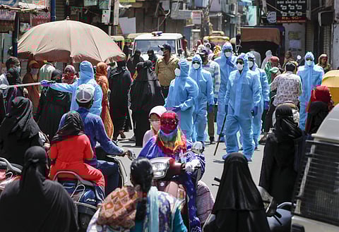Police personnel wearing protective suit urge people to maintain social distance following relaxation of restrictions for few hours during the nationwide lockdown to curb the spread of coronavirus in Ahmedabad Wednesday April 22 2020. (Photo | PTI)
