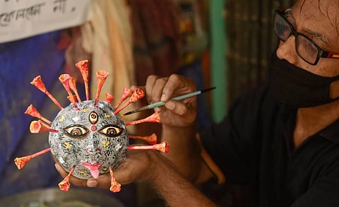 An artist makes a coronavirus themed idol for Puja festivities at a workshop at Kumartuli . (Photo | PTI)