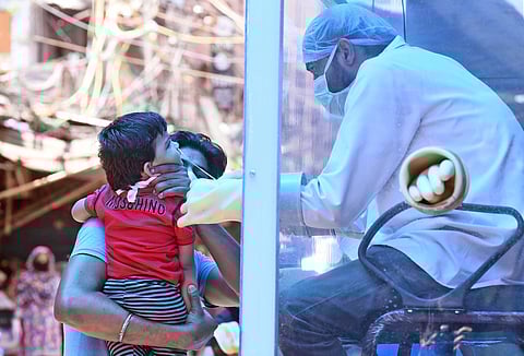 A health worker collects swab samples from a kid at a mobile COVID-19 testing centre. (Photo | Parveen Negi, EPS)