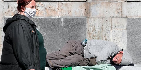 A homeless man wearing a mask sleeps outside the main railway station. (Photo | AP)