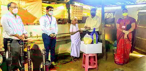Representatives of Bharathiar University handing over ration to Kamalathal at Vadivelampalayam in Coimbatore (Photo| EPS).