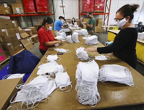 In this Thursday, April 23, 2020 photo, Kenia Anzarado, right, and Mae Catalan, left, works on finishing and packing face masks at the Georgia Expo in Suwanee, Ga. The company has pivoted from sewing curtains to sewing cloth face masks. As business restri