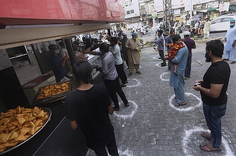 People maintaining a level of social distancing wait their turn to get traditional food from a bakery to break their fast on the first day of Ramadan, in Lahore, Pakistan. Saturday, April 25, 2020. (Photo | AP)